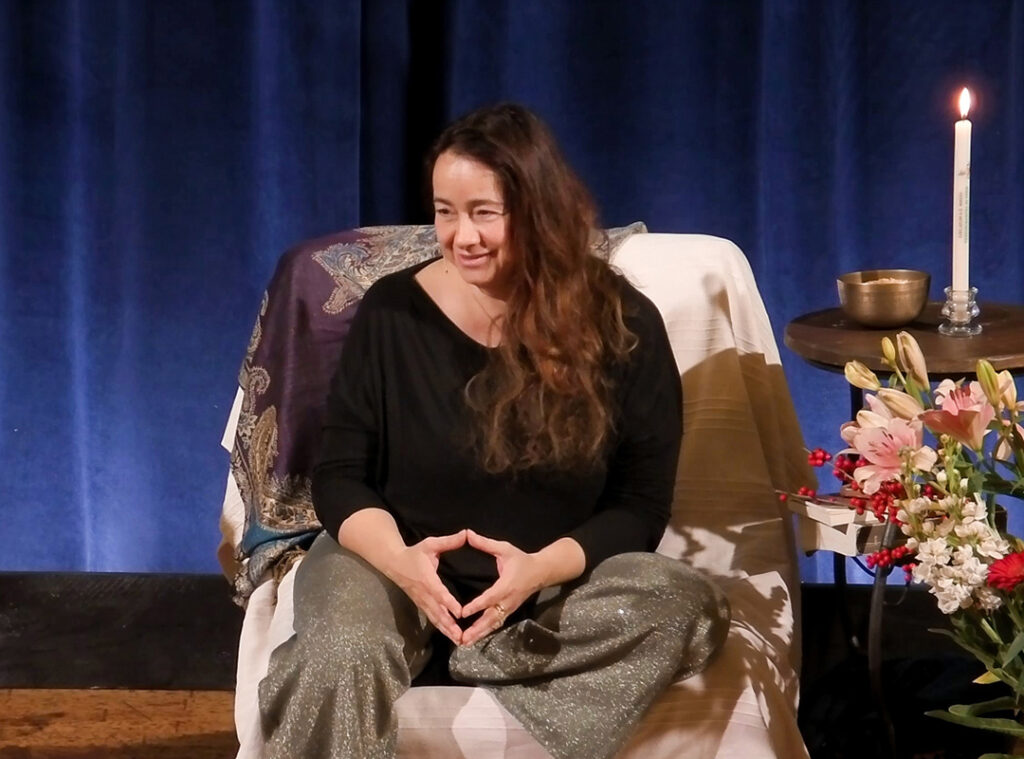 Shakti Caterina Maggi Teaching with black vest and smiling looking on the left